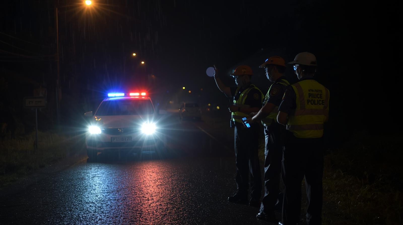 Thai police conduct a late-night drunk driving checkpoint on a city road.