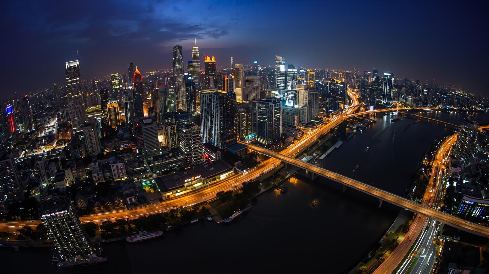 A wide view of Bangkok’s downtown skyline at night, filled with lights and activity