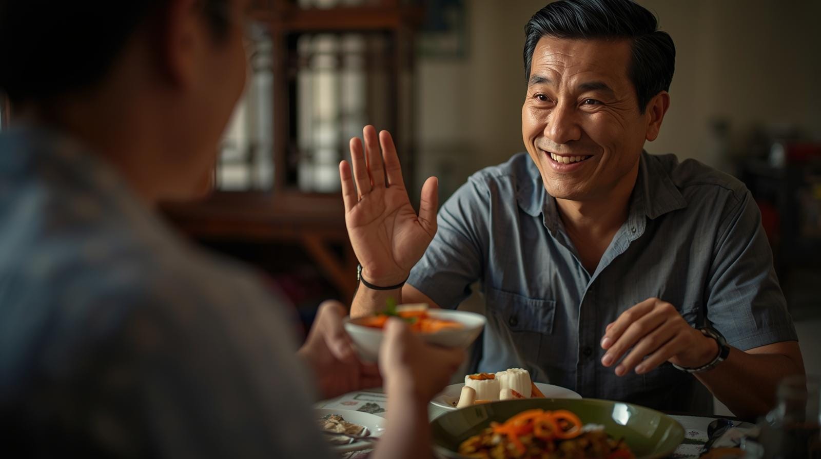 At a Thai family dinner, a local host offers a dish to a foreign guest who smiles and hesitates politely before accepting, illustrating mutual generosity and respect.