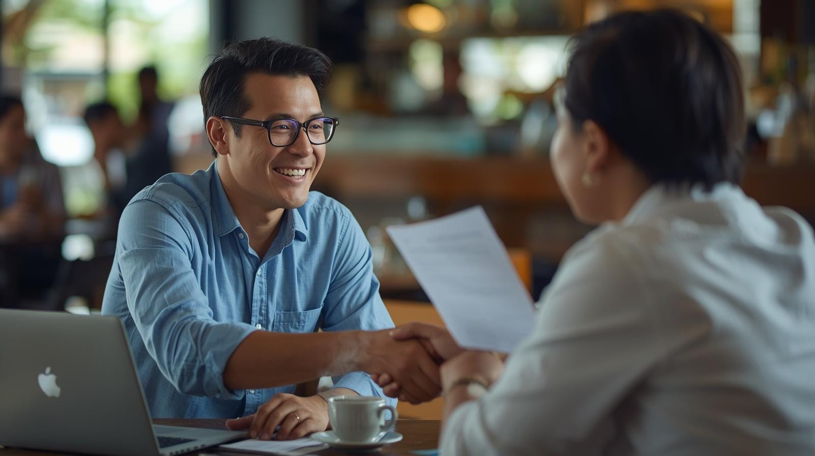 Expatriate discussing business with a Thai professional over coffee.